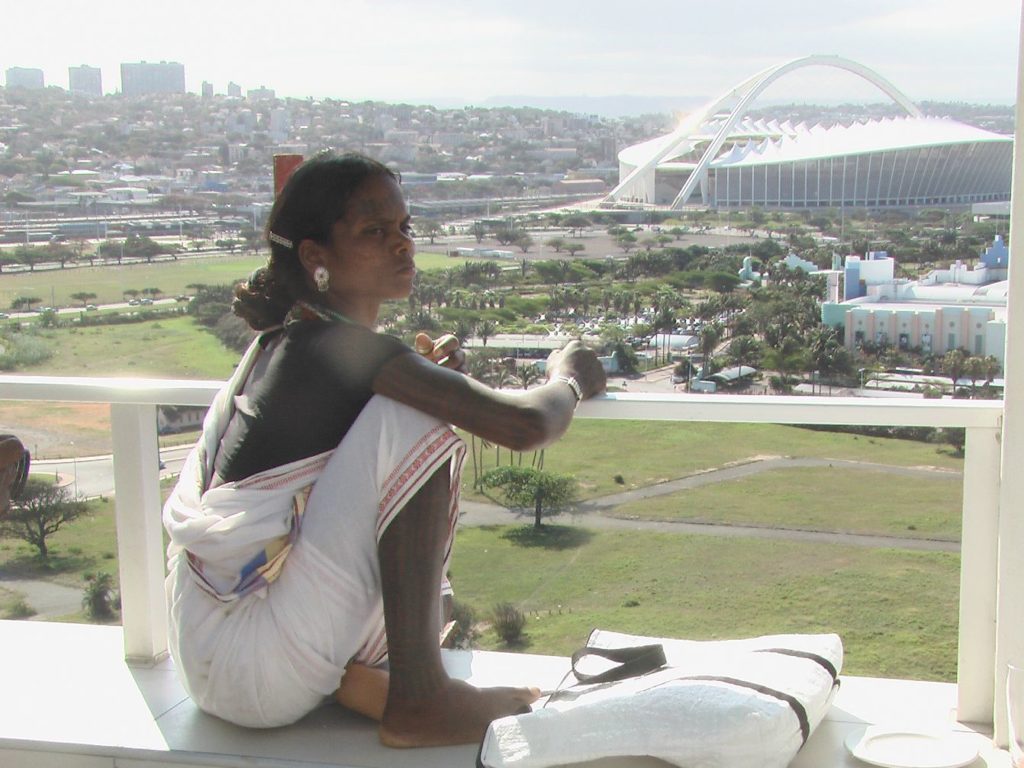 Indian indigenous woman sitting on balcony with city view.
