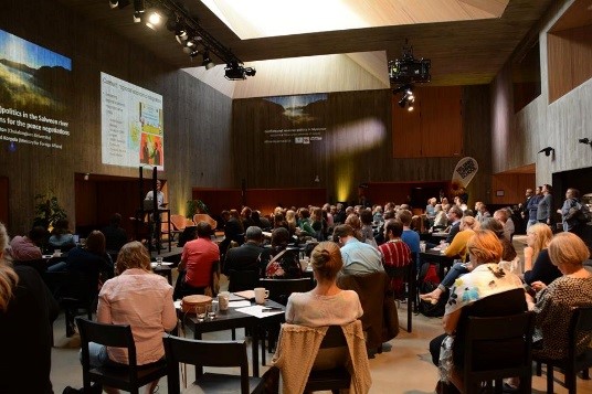 Audience follows presentation in a modern meeting hall.
