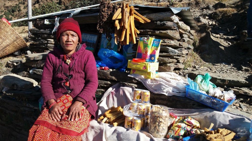 Woman on stone stairs with small items for sale.