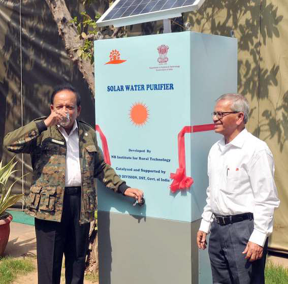 Two men standing in front of a box-like machine.