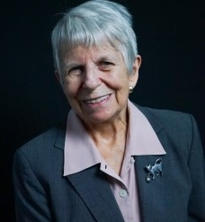 Smiling gray haired woman in a jacket suit.